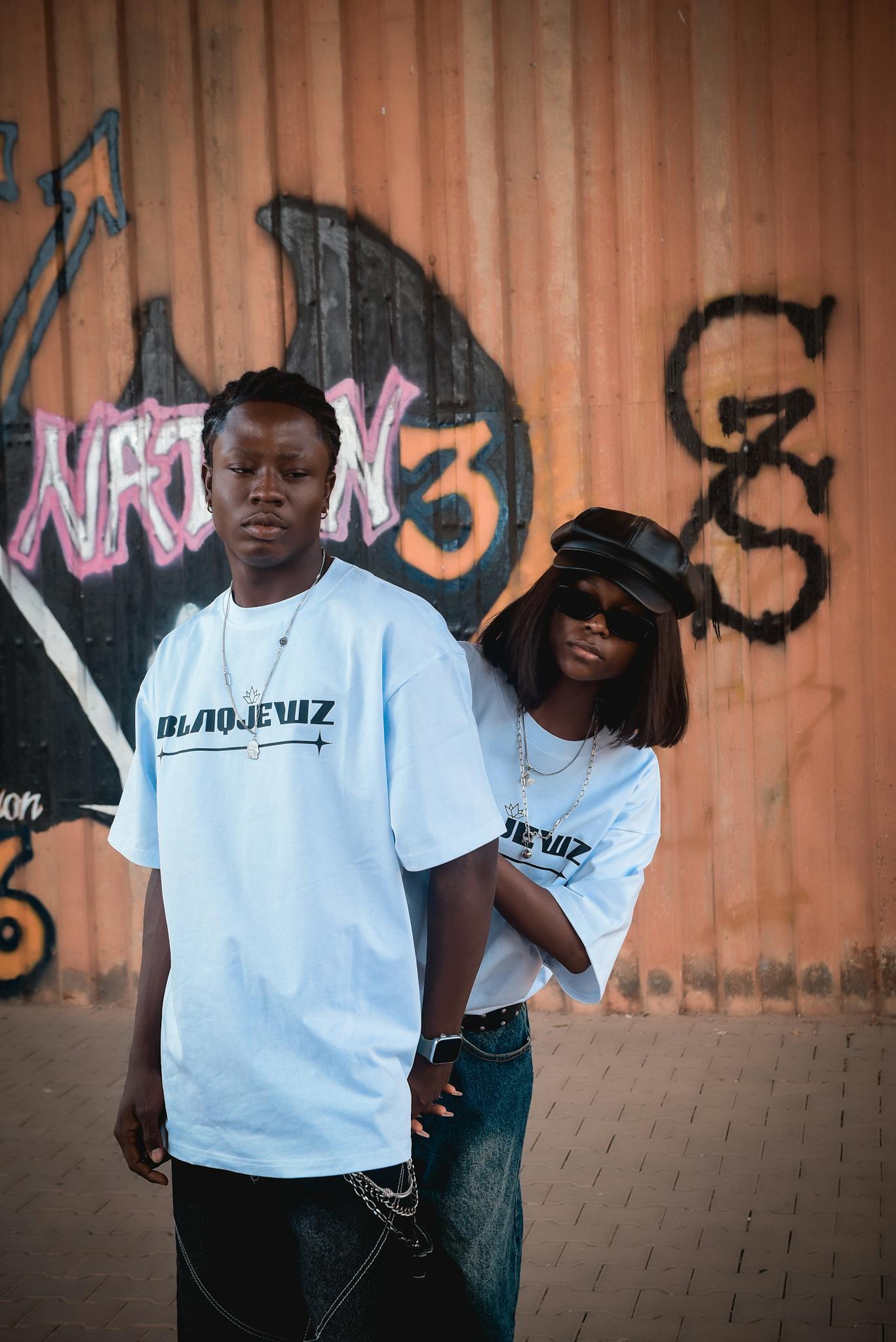 Fashionable duo in streetwear against vibrant graffiti wall
